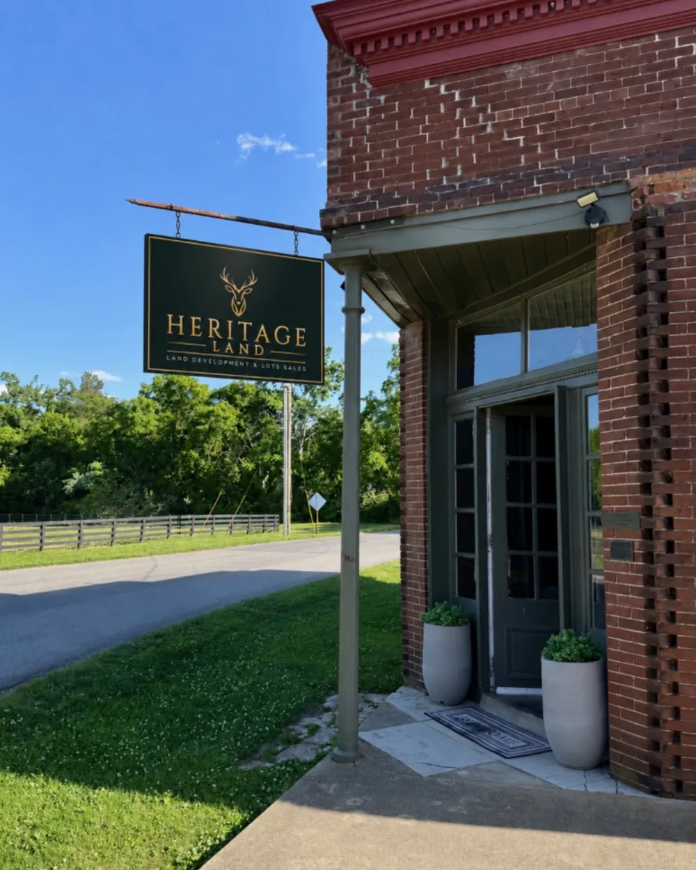 The Heritage Land office — a red brick building on Thompsons Station Road West with the Heritage Land sign hanging at the entrance